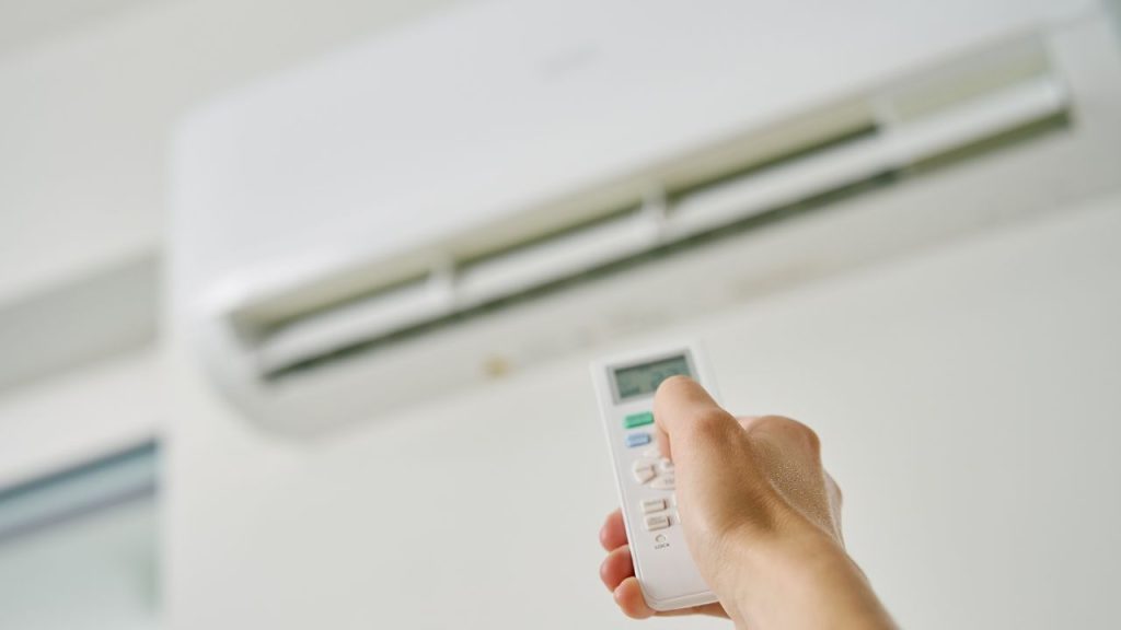 a person using a remote to control the air conditioner
